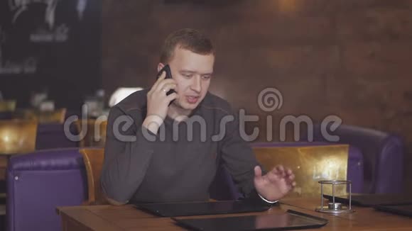 年轻人坐在咖啡馆的桌子旁打电话视频的预览图