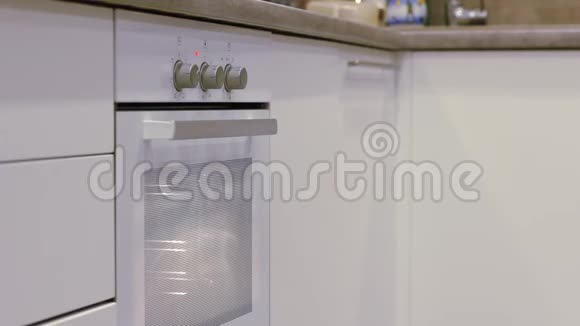 男人手打开白色厨房上的白色烤箱极简主义视频的预览图