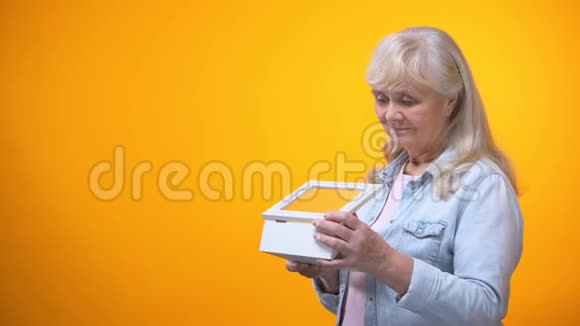 心烦意乱的退休女士用珍贵的东西看着盒子怀念过去视频的预览图