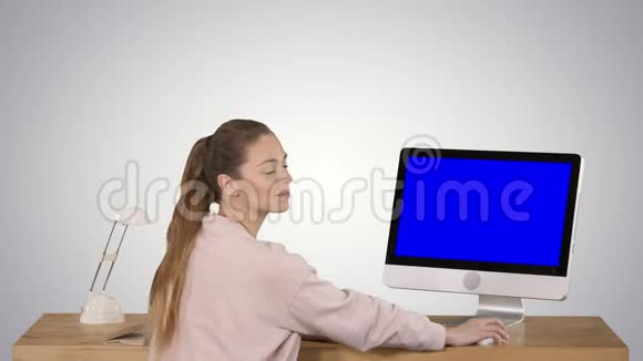 一位开朗的女士坐在桌子旁办公室里有一台电脑她看着摄像机微笑着展示着蓝屏模型视频的预览图