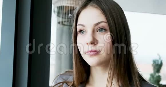 年轻迷人的女性的肖像她看着靠近窗户的办公室上的相机很漂亮的女人关闭视频的预览图