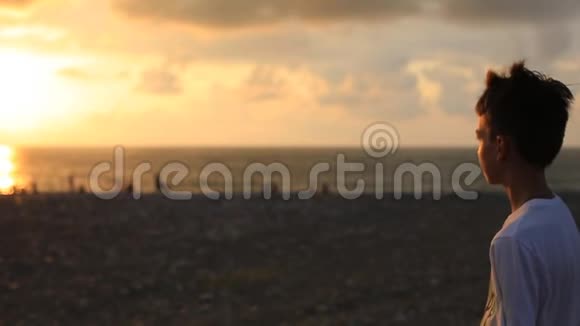 日落时分一个十几岁的男孩在海边的肖像视频的预览图