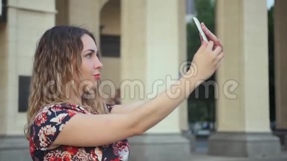 有魅力的女孩拍一个自拍视频卷曲的女人在度假时有一个视频流城市的远距离关系视频的预览图