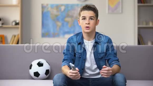 令人兴奋的青少年学生在电视上观看足球比赛为国家队加油视频的预览图