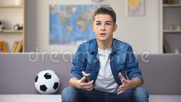 在电视上看足球赛的焦虑少年对球队输球感到不快视频的预览图