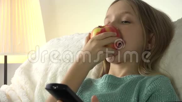 儿童在看电视时吃苹果女孩在沙发上放松生活教练视频的预览图