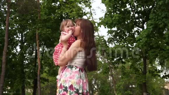 妈妈抱着一个婴儿在温暖的绿色公园里笑视频的预览图