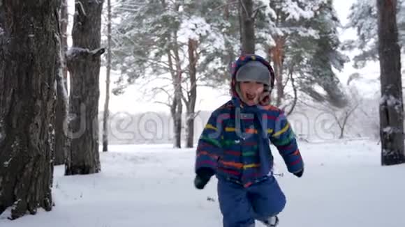 开心地笑着的小孩子朝镜头跑去在一片白雪皑皑的森林或公园里娱乐体育和视频的预览图