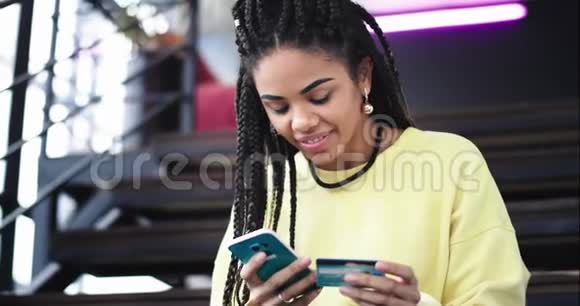 一位美丽的有魅力的非洲年轻女性使用智能手机购买或使用她的银行检查东西的画像视频的预览图