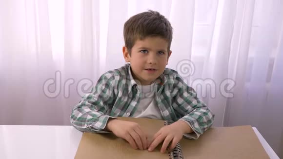 视力受损的小男孩在桌旁阅读盲文书上面有盲人用的字体符号视频的预览图