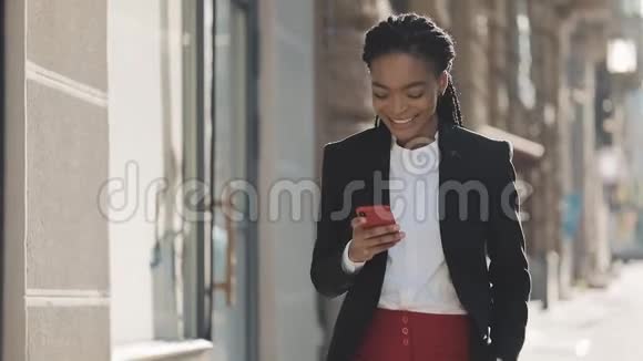 微笑着迷人的黑人商务女性使用智能手机在市中心行走黑色时尚可怕的家伙非洲裔视频的预览图