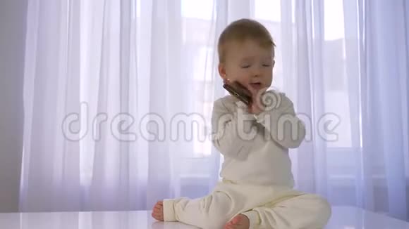 现代的童年可爱有趣的宝宝在明亮的房间里玩手机聊天视频的预览图