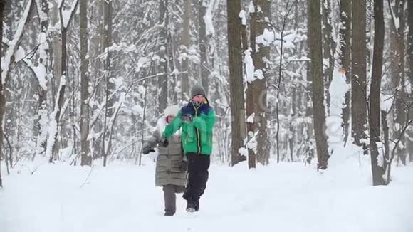 孩子们在冬天的森林里互相追赶1一个小女孩在雪地里撞倒了她的弟弟视频的预览图