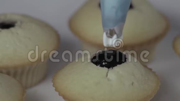 宏慢动作糖果师在纸杯蛋糕上涂上奶油视频的预览图