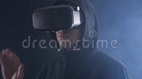 特写未来派男子戴着VR耳机未来派男子使用虚拟现实眼镜在一个黑暗的烟雾房间视频的预览图