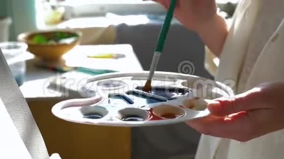 画家工作微笑艺术工匠女性混合颜料在调色板与精细的画笔同时工作的新绘画在视频的预览图