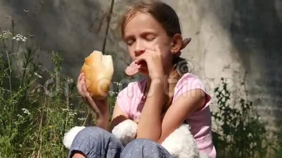被遗弃的房子里悲伤的孤儿不快乐的流浪女孩吃面包香肠4K视频的预览图
