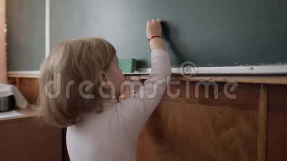女孩在教室里用粉笔在黑板上画画教育进程视频的预览图