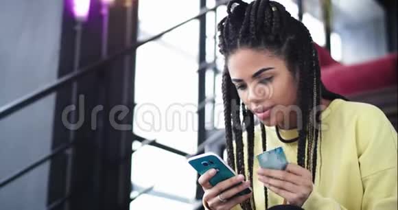 有魅力的非洲女士特写用手机和银行卡在楼梯上买东西视频的预览图