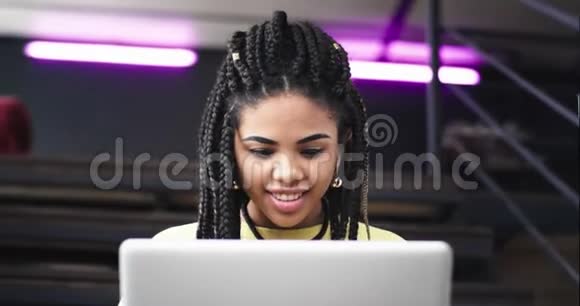 肖像漂亮的非洲女士用笔记本和银行卡在网上买东西她坐在楼梯上视频的预览图
