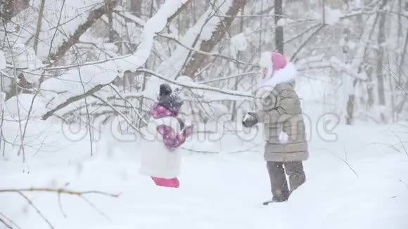 冬季森林两个快乐的小女孩站在彼此面前把雪扔了起来视频的预览图