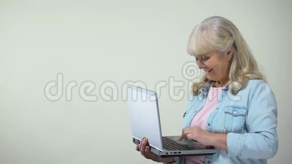老年女士在笔记本电脑上打字显示拇指向上退休人员的电脑素养视频的预览图