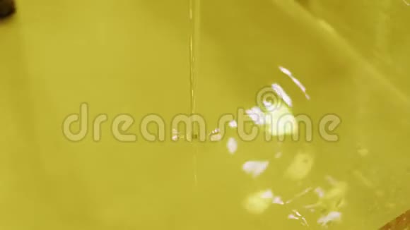 黄色粘稠液体油从水龙头流向容器视频的预览图