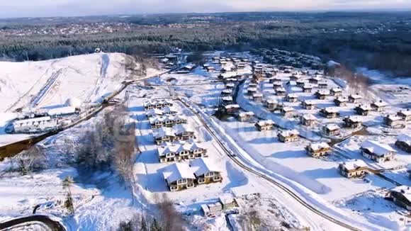 在一个阳光明媚的冬日飞过被雪覆盖的城市住宅区旅途美丽房屋的空中楼阁视频的预览图