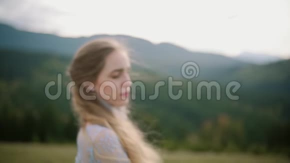 年轻女子的画像头发随风飘动看着山上的日落慢动作视频的预览图