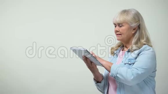 体贴的老太太在平板电脑上滚动屏幕网上银行应用程序视频的预览图