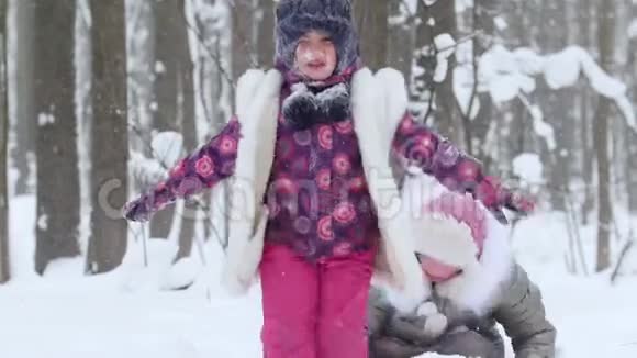 两个小女孩在冬天的森林里玩雪女孩脸上的雪视频的预览图