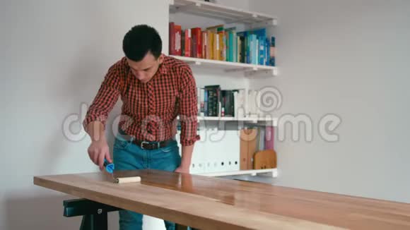 穿着格子衬衫的人正在整理木制橡木桌子家里有一个滚筒视频的预览图