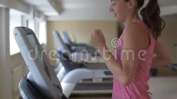年轻女子在健身房的跑步机模拟器上跑步视频的预览图