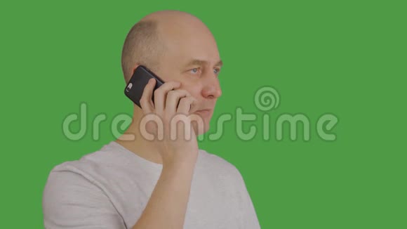 绿色背景下通过手机收听和交谈的成年男子视频的预览图
