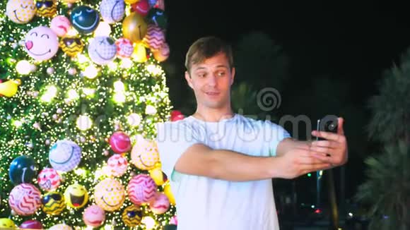 热带城市圣诞树和棕榈树背景下的快乐男人新年旅行的概念视频的预览图