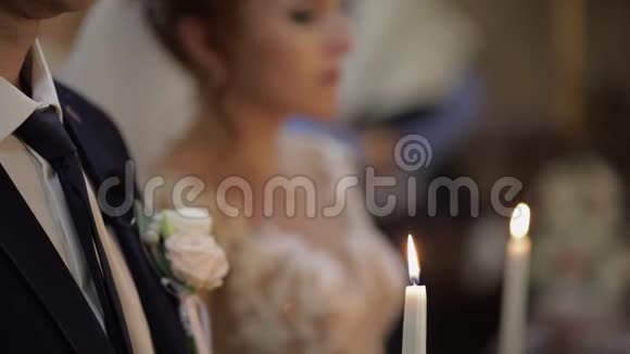新娘和新郎站在教堂里手里拿着蜡烛视频的预览图