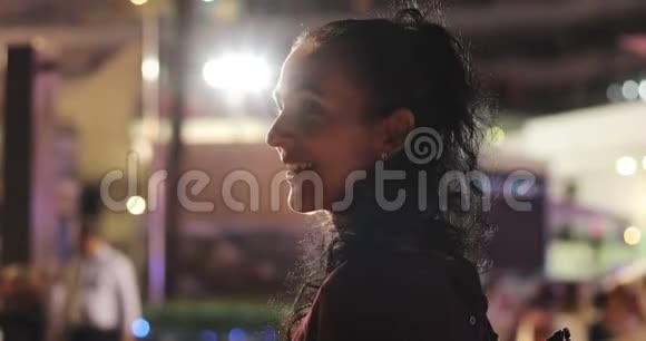 一个美丽的成熟女人卷曲的黑发在城市过夜视频的预览图