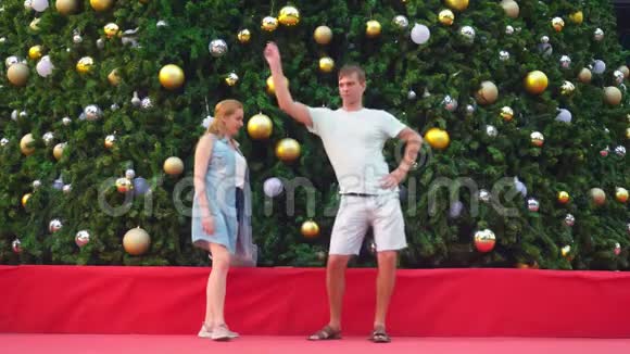 快乐的一对男女在热带城市圣诞树的背景下跳舞新年的概念视频的预览图