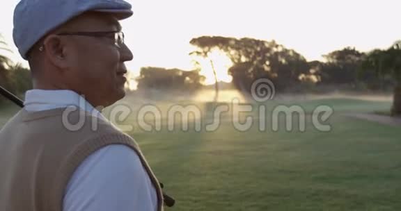 高尔夫球手肩扛高尔夫球杆站在高尔夫球场上视频的预览图