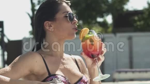 喜气洋洋的戴着墨镜喝着鸡尾酒的女人穿比基尼的孤独女士的休闲视频的预览图