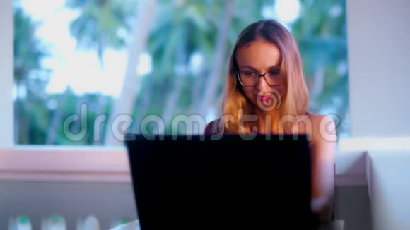 戴眼镜的女孩在手提电脑上对着棕榈树发短信视频的预览图