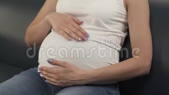 被女人的手碰到的怀孕的腹部近处摄像机慢慢地自下而上移动女人微笑看着视频的预览图