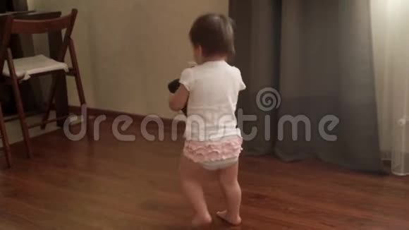 小女孩拿着一个便携式音乐柱慢动作地走在地板上视频的预览图