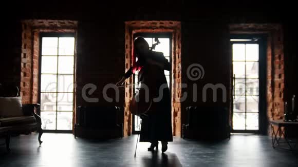 一个女人在演播室里演奏大提琴的黑暗轮廓视频的预览图