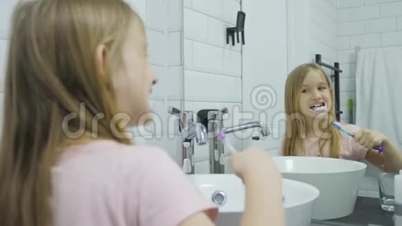 青春期前的女孩刷牙在浴室里洗脸视频的预览图