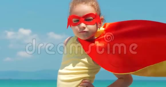 在超级英雄服装穿着红色斗篷和英雄面具的特写肖像美丽的小女孩土地视频的预览图