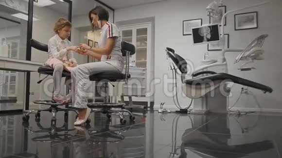在牙科医生办公室里一个正在学习刷牙的小女孩的X光头正畸医生视频的预览图