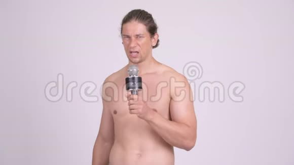 肌肉发达的赤膊男子用麦克风唱歌视频的预览图