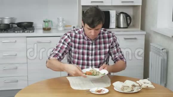 饥肠辘辘的男人正在家里的厨房桌子上煮沙瓦玛很快就吃了这个视频的预览图