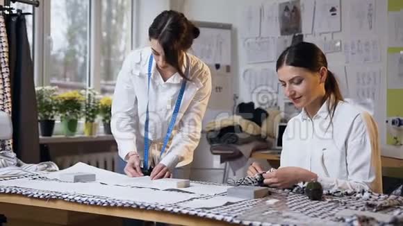 两个女裁缝在缝纫工作室缝制一块布视频的预览图